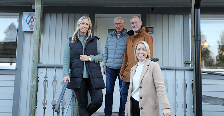 Två vuxna står vid en cykel med barnsulky och pratar.