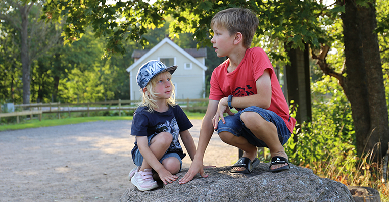 Två barn sitter på en stor sten.