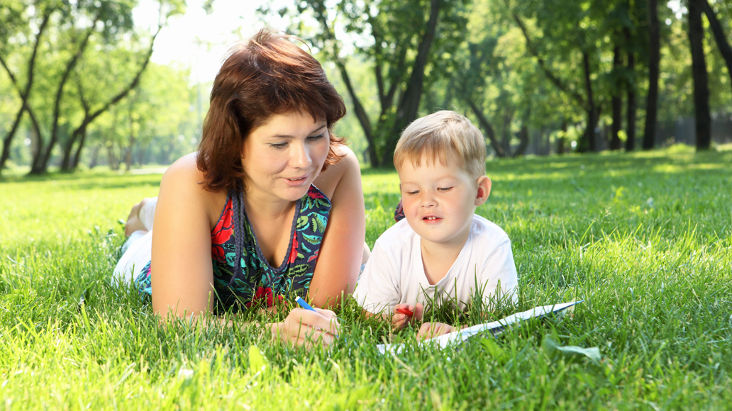 Mamma och son läser i parken