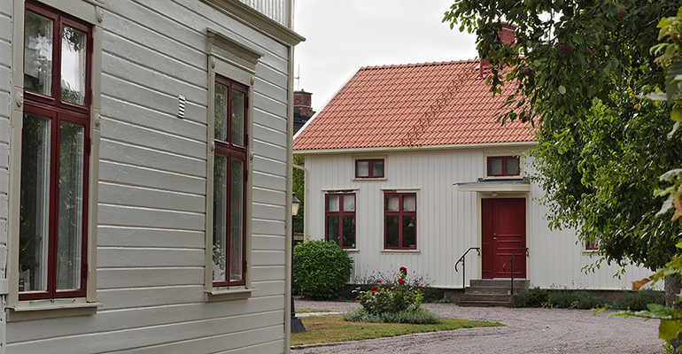 En gårdsmiljö med trähus målade i en behaglig beigegrå kulör.