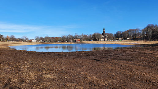 En sjö har bildats med Varnhems klosterkyrka i bakgrunden.