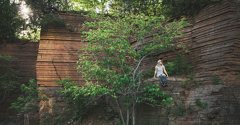 En tjej sitter på en klippavsats på ett platåberg