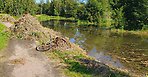 En långsmal sjö med en cykelbana bredvid. Bredvid sjön finns en rostig cykel.