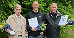 Tre personer med blommor och diplom